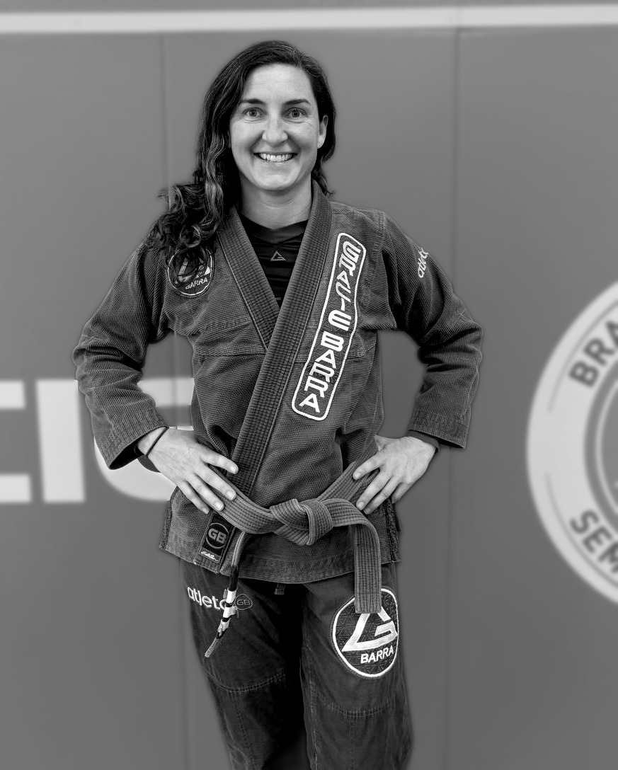 Coach Heidi Cogburn, brown belt instructor at Gracie Barra Seminole, standing full-figure in her gi on the mat